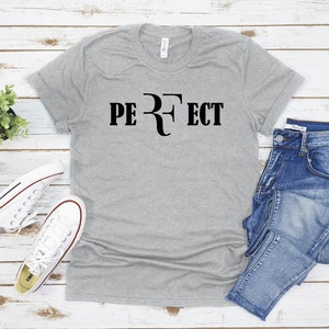 Op de afbeelding: Een grijs T-shirt met de tekst "PERFECT" en een tennisracketlogo in zwart.