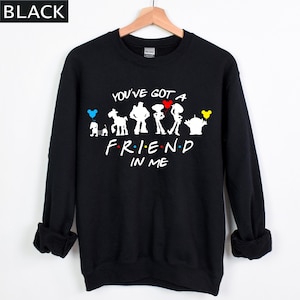 Puede incluir: Sudadera negra con la frase "YOU'VE GOT A FRIEND IN ME" y siluetas de personajes de dibujos animados. El dise&ntilde;o presenta personajes de la pel&iacute;cula Toy Story. La sudadera tiene mangas largas y cuello redondo.