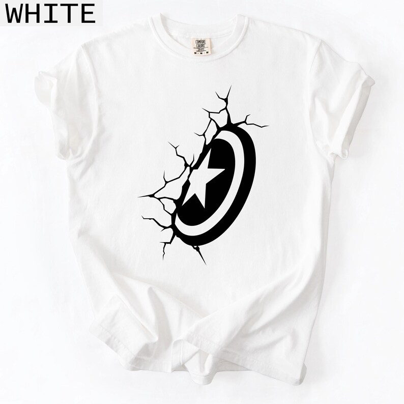 Pode incluir: Camiseta branca com um gr&aacute;fico preto e branco de um escudo com uma estrela, parecendo romper a superf&iacute;cie. A palavra "WHITE" est&aacute; impressa no canto superior esquerdo. Gola redonda, mangas curtas. Roupa casual.