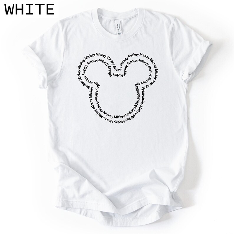 Peut inclure: T-shirt blanc avec un motif de t&ecirc;te de Mickey Mouse noir. La t&ecirc;te est form&eacute;e par le mot "Mickey" r&eacute;p&eacute;t&eacute; en cercle. Le mot "WHITE" est imprim&eacute; dans le coin sup&eacute;rieur gauche.