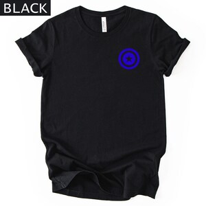 Pu&ograve; includere: T-shirt nera con un design grafico blu e nero sul davanti. La grafica &egrave; un cerchio blu con una stella blu al centro. La parola "BLACK" &egrave; in testo bianco nell'angolo in alto a sinistra.