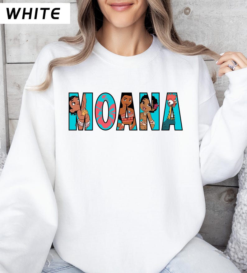May include: White sweatshirt with the word "MOANA" in a colourful cartoon design. The letters are outlined in teal, with a coral-coloured "O". The design includes cartoon characters from the movie.