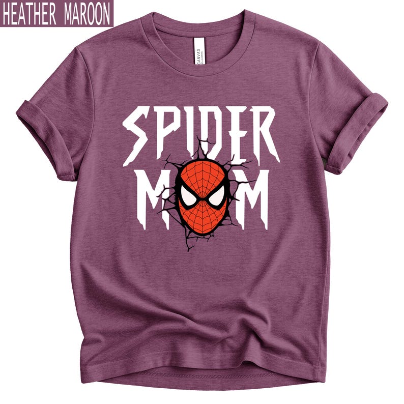May include: Heather maroon t-shirt with rolled sleeves. The shirt features the text "SPIDER MOM" in white, with a red and black spider mask graphic in the centre. The shirt is made of a soft material.