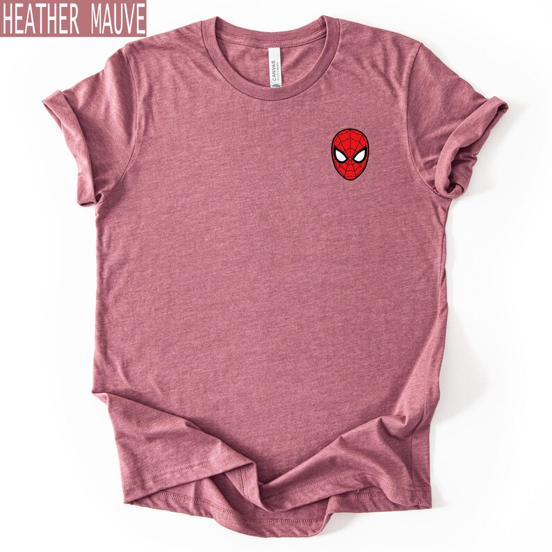 Puede incluir: Camiseta color malva jaspeado con un peque&ntilde;o gr&aacute;fico de la m&aacute;scara de Spider-Man en el pecho. La camiseta es de color liso y tiene cuello redondo. El texto "HEATHER MAUVE" est&aacute; en un recuadro en la esquina superior izquierda.