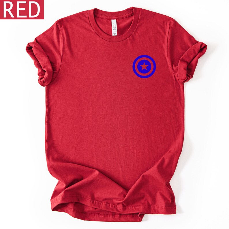 Pu&ograve; includere: T-shirt rossa con grafica blu e bianca sul petto in alto a sinistra. La grafica &egrave; un cerchio blu con una stella blu al centro. La parola "RED" &egrave; in una casella bianca nell'angolo in alto a sinistra.