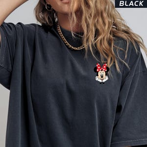 May include: Black oversized t-shirt with a small Minnie Mouse graphic on the front. The graphic shows Minnie Mouse with a red bow with white polka dots. The word "BLACK" is printed in white at the top.
