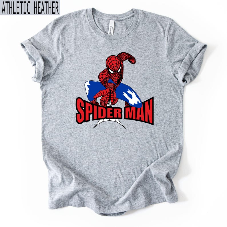 Op de afbeelding: Athletic heather grijs t-shirt met een Spider-Man afbeelding. Het ontwerp bevat een rood en zwart Spider-Man figuur, een blauw webdesign en de rode tekst "SPIDER-MAN".