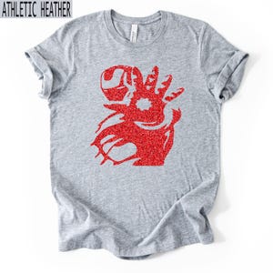 Puede incluir: Camiseta gris jaspeado con un gr&aacute;fico de purpurina roja. El gr&aacute;fico es un dise&ntilde;o estilizado de una cara y una mano. El texto "ATHLETIC HEATHER" est&aacute; en una caja blanca en la parte superior de la camiseta.