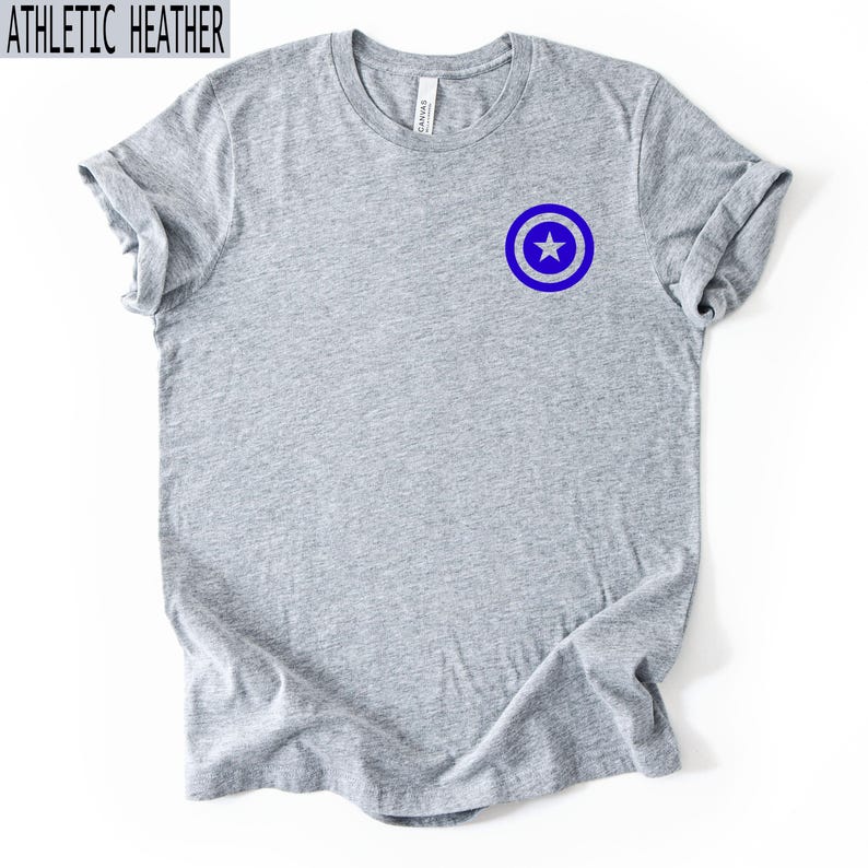 Pu&ograve; includere: T-shirt grigio atletico con un'emblema a stella blu e bianca sul petto sinistro. La maglietta ha un girocollo e maniche corte. Il testo "ATHLETIC HEATHER" &egrave; in alto.