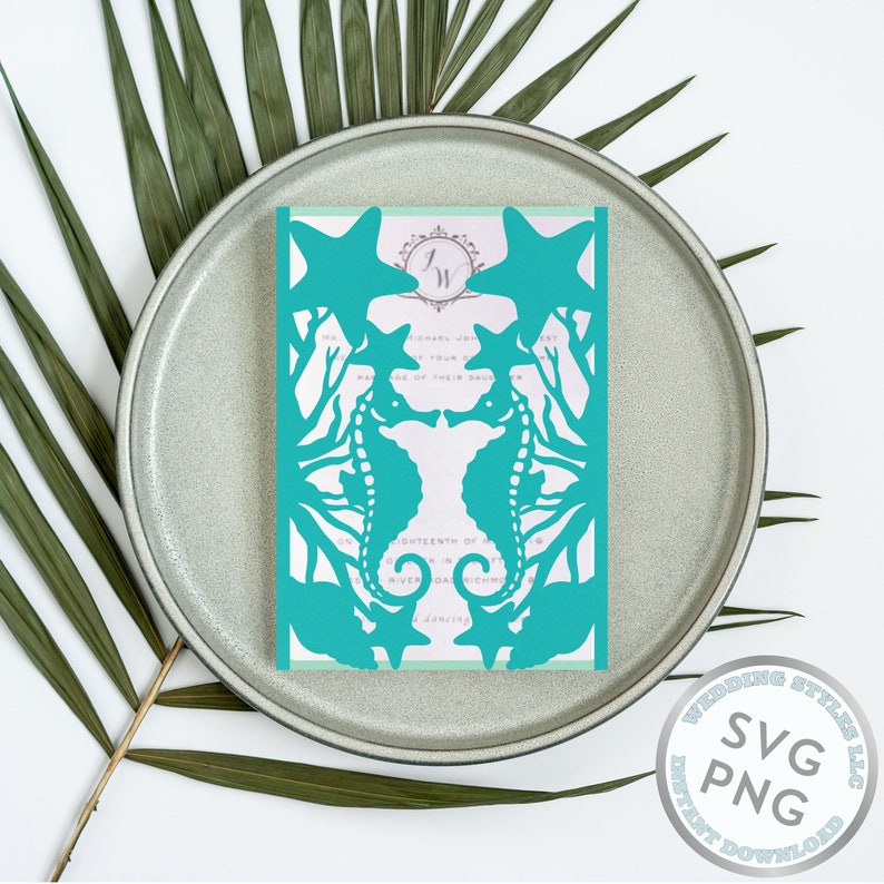 May include: Teal blue laser cut wedding invitation with a design of two seahorses facing each other and a starfish above them. The invitation is on a gray plate with green palm leaves in the background.