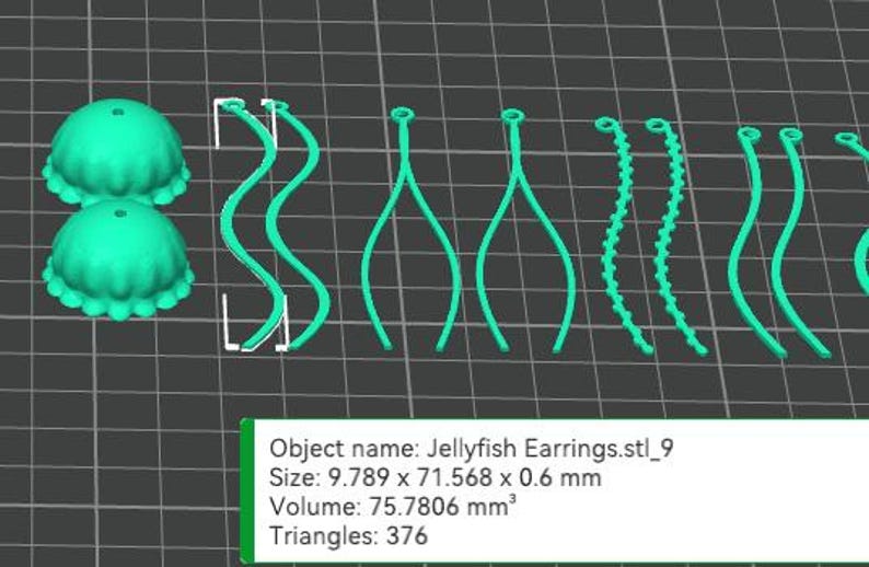 May include: A 3D printed set of turquoise blue jellyfish earrings. The earrings are made up of two parts: a round, textured jellyfish body and a long, thin, dangling tentacle. The tentacles are available in a variety of styles, including wavy, straight, and beaded.