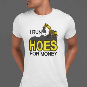 May include: White t-shirt with a yellow excavator digging a hole with the text "I run hoes for money" printed on it.