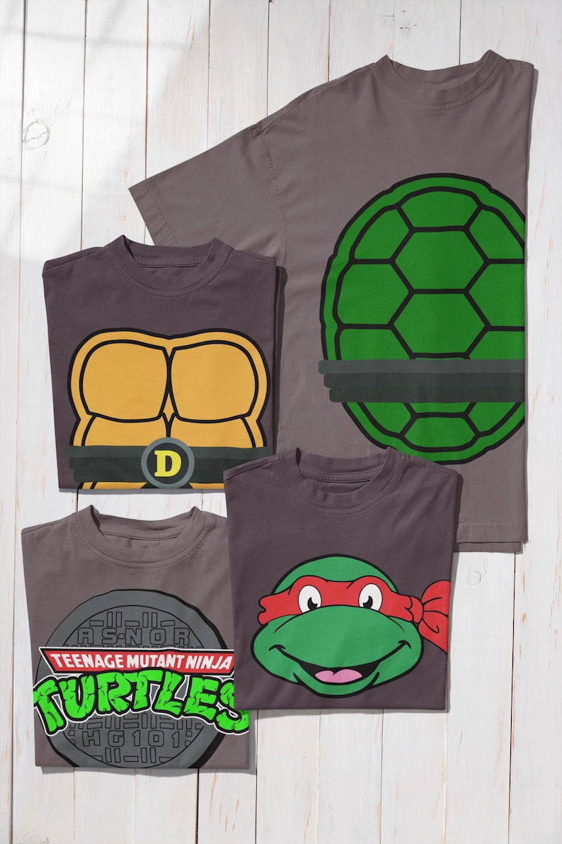 May include: Four gray t-shirts with Teenage Mutant Ninja Turtles designs. One shirt features a green turtle shell, another has a yellow chest design with a "D" belt buckle, and a third displays a turtle face with a red mask. The fourth shirt has the TMNT logo.