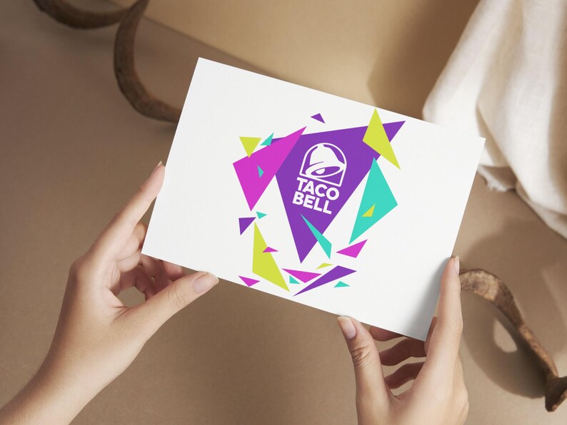 Puede incluir: Una tarjeta rectangular blanca que presenta el logotipo de Taco Bell en blanco centrado dentro de un gran tri&aacute;ngulo morado. El dise&ntilde;o est&aacute; rodeado por varios tri&aacute;ngulos geom&eacute;tricos dispersos en tonos vibrantes de verde lima, magenta y cian.