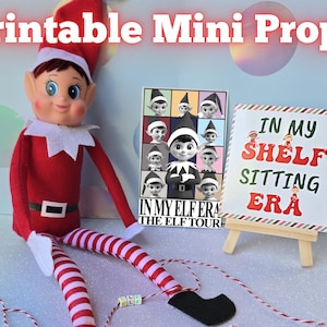 Puede incluir: Mini accesorios imprimibles para la fotografía de elfos en la estantería. Los accesorios incluyen un cartel que dice "In My Shelf Sitting Era" y un cartel con un collage de fotos de elfos que dice "In My Elf Era The Elf Tour".