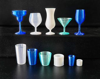 May include: A collection of 10 clear and blue glass cups and shot glasses. The glasses are arranged in two rows on a black surface.