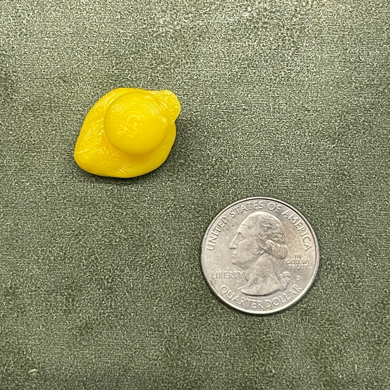 Puede incluir: Un peque&ntilde;o pato de goma amarillo. El pato est&aacute; sentado sobre una superficie verde.