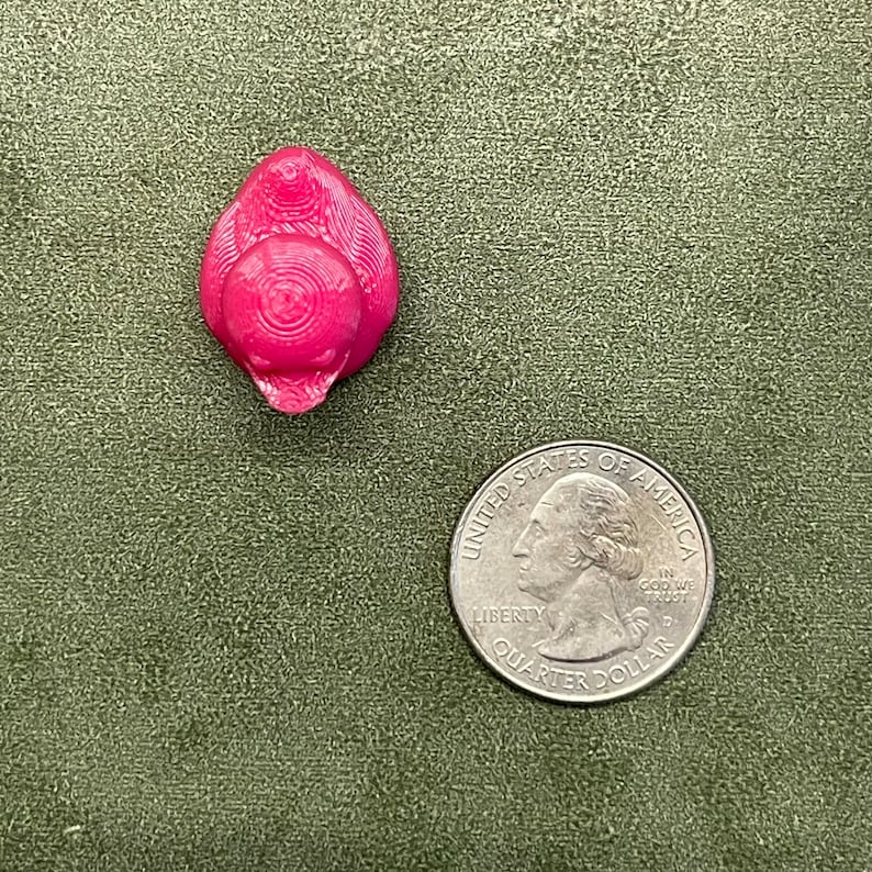 Puede incluir: Una peque&ntilde;a figurita de cer&aacute;mica rosa de un p&aacute;jaro con una superficie texturizada detallada.