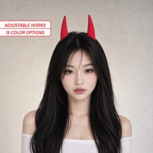 May include: A red devil horn headband on a person with black hair. The text on the image says 'Adjustable Horns' and '15 Colour Options'. The person is wearing a white top.