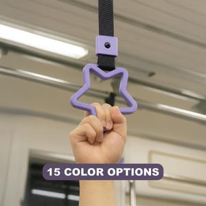 May include: A light purple star-shaped handle attached to a black strap. The handle is designed for gripping and features a smooth, matte finish. A rectangular purple text box at the bottom displays the white text 15 COLOR OPTIONS.