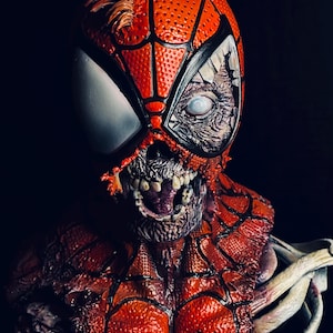 May include: A close-up of a zombie Spider-Man bust. The bust is made of painted resin and features a detailed sculpt of Spider-Man's head and torso. The bust is painted in a red and black color scheme, with a white spider logo on the chest. The bust is also painted with a realistic zombie effect, with exposed bones and flesh.