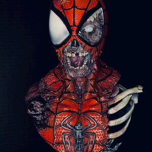 May include: A detailed bust of a zombie Spider-Man, with a red and black costume, a decaying face, and exposed bones. The bust is on a base with the words "Marvel Zombies" printed on it.
