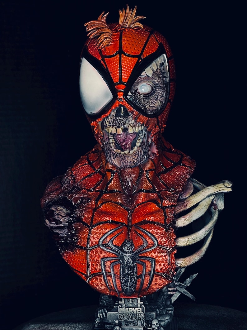 May include: A detailed bust of a zombie Spider-Man, with a red and black costume, a decaying face, and exposed bones. The bust is on a base with the words "Marvel Zombies" printed on it.