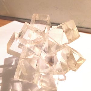 Puede incluir: Un cúmulo de cristales transparentes con múltiples facetas, que se asemeja a una estrella en explosión.