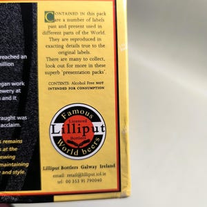 May include: A portion of a box with text and a circular logo. The logo reads "Famous Lilliput World beers." Text on the box states the pack contains labels from around the world, reproduced in detail. The text also states the contents are alcohol-free.