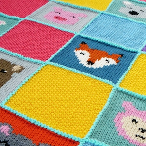 Puede incluir: Una manta de bebé tejida con un diseño de patchwork que presenta varias caras de animales, incluyendo un oso, un zorro, un conejito, un cerdo y un koala. La manta está hecha con hilo de diferentes colores, incluyendo azul, amarillo, rosa, rojo y gris.
