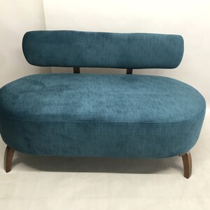 May include: A teal blue oval-shaped sofa with a curved back and wooden legs.