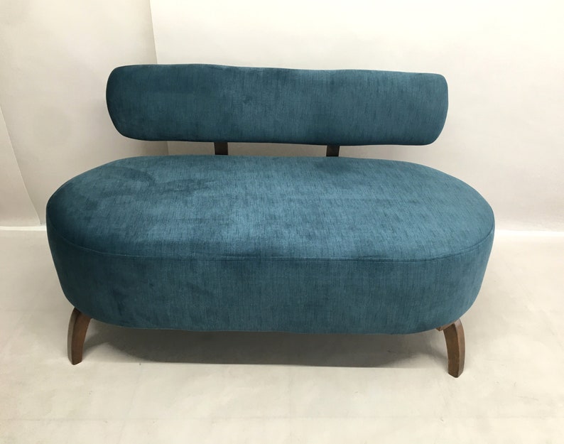 May include: A teal blue oval-shaped sofa with a curved back and wooden legs.