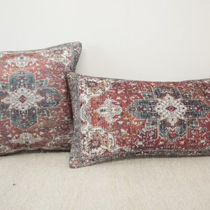 Puede incluir: Dos almohadas decorativas con un diseño estampado en rojo, azul y blanco. Las almohadas tienen un diseño tradicional, ornamentado e intrincado.