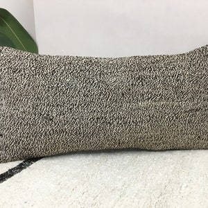 May include: A black and white patterned throw pillow with a rectangular shape. The pillow is made of a textured fabric.
