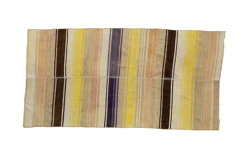 May include: Rectangular textile with vertical stripes in shades of beige, brown, yellow, and purple. The stripes are of varying widths. The textile appears to be hand-stitched in the middle. The edges are frayed.