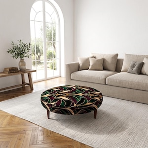 May include: A round ottoman featuring a velvet-like fabric with a repeating fan-shaped pattern in shades of deep green, dark purple, black, and gold. The piece is supported by four short, tapered wooden legs in a medium brown finish.