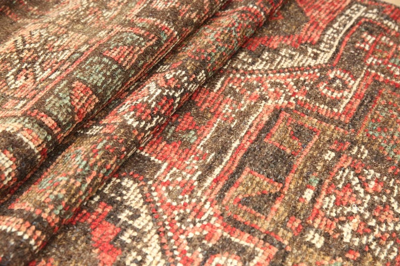 a close-up view of a colorful, intricately patterned rug or carpet with a variety of geometric shapes and designs in shades of red, orange, and brown.