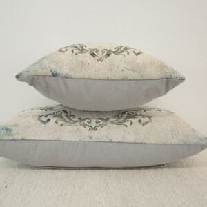 Puede incluir: Dos almohadas decorativas con fondo blanco y estampado floral verde. Las almohadas est&aacute;n apiladas una encima de la otra.