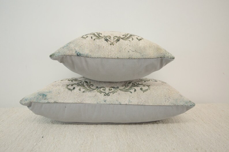 Puede incluir: Dos almohadas decorativas con fondo blanco y estampado floral verde. Las almohadas est&aacute;n apiladas una encima de la otra.