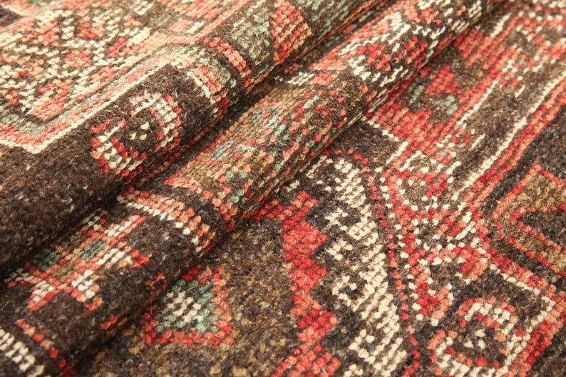 a close-up view of a colorful, intricately patterned rug or carpet with a variety of geometric shapes and designs in shades of red, orange, and brown.