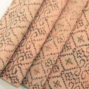 May include: A folded pink and brown patterned rug with a green fringe. The rug has a floral design.