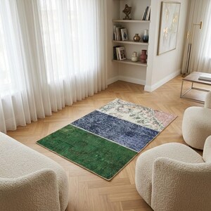 May include: A rectangular area rug featuring three distinct horizontal sections: a solid deep green panel, a textured navy blue middle section, and a cream-colored end panel decorated with a faded floral pattern in shades of pink and green.
