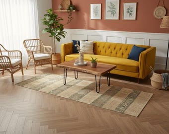 May include: A rectangular area rug featuring a repeating pattern of wide beige stripes alternating with narrower, textured olive green bands with intricate geometric motifs, laid out on a light brown herringbone patterned wooden floor.