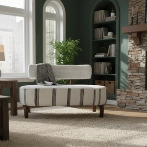 Puede incluir: Un banco color crema con rayas verticales negras y respaldo a juego. El banco tiene patas de madera oscura y una manta a cuadros blancos y negros sobre el respaldo. El banco está en una habitación con una pared verde y una chimenea de piedra.