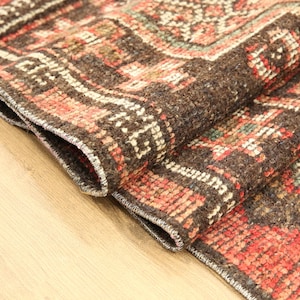 A close-up view of a colorful, intricately patterned rug on a wooden surface.