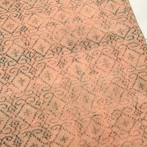 May include: A pink and black patterned rug with a geometric design. The rug is made of a woven material and has a distressed look.
