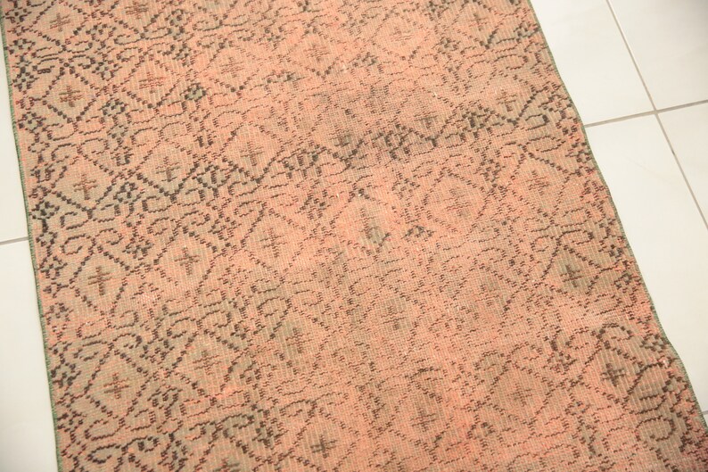 May include: A pink and black patterned rug with a geometric design. The rug is made of a woven material and has a distressed look.