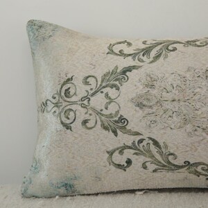 Puede incluir: Una almohada blanca con un patr&oacute;n floral verde y blanco. La almohada est&aacute; hecha de una tela suave y texturizada.