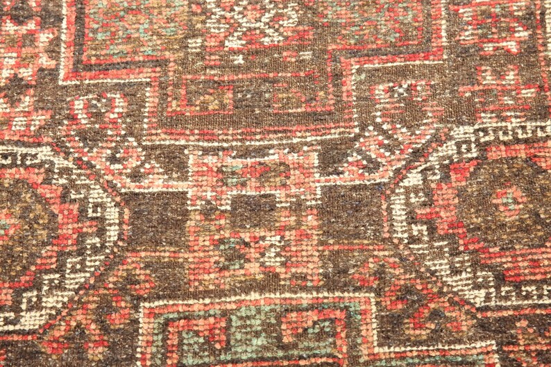 a close-up view of a colorful, intricately patterned rug or carpet with a variety of geometric shapes and designs in shades of red, orange, and green.