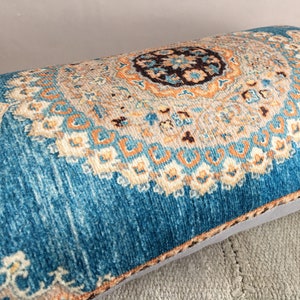 May include: A blue and orange patterned throw pillow with a decorative design. The pillow is made of a soft, plush fabric and has a subtle sheen.